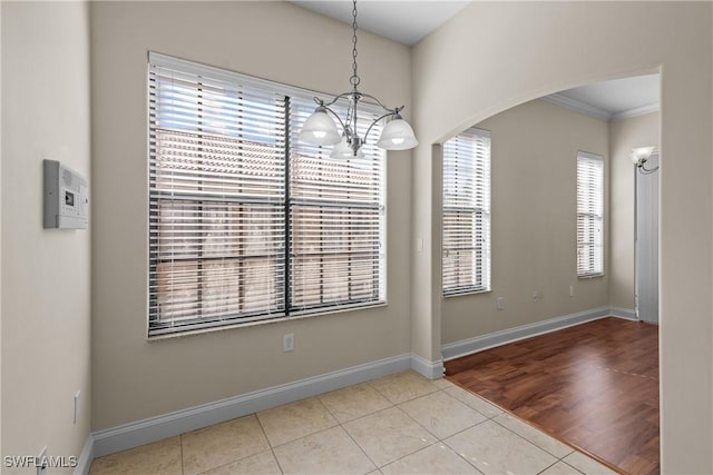 unfurnished dining area featuring crown molding, a healthy amount of sunlight, a notable chandelier, and light hardwood / wood-style floors