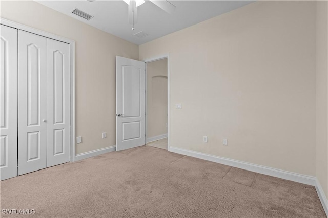 unfurnished bedroom with light carpet, a closet, and ceiling fan