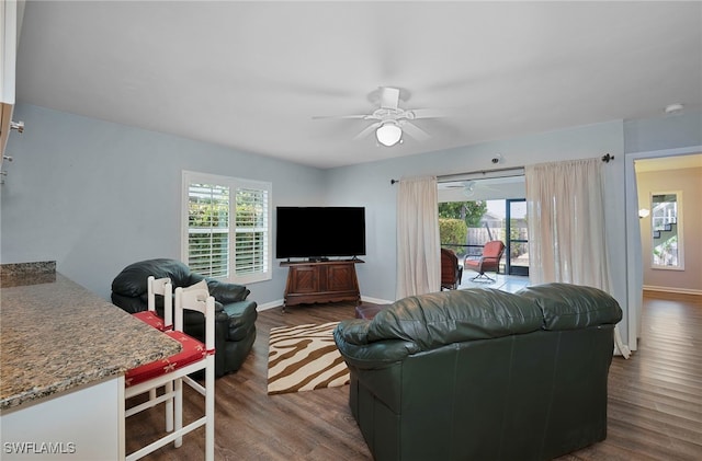 living area with ceiling fan, plenty of natural light, baseboards, and dark wood finished floors