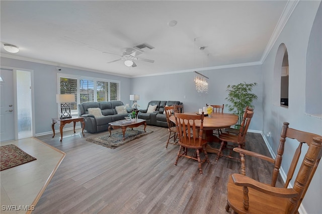 dining space featuring hardwood / wood-style floors, ceiling fan with notable chandelier, and crown molding