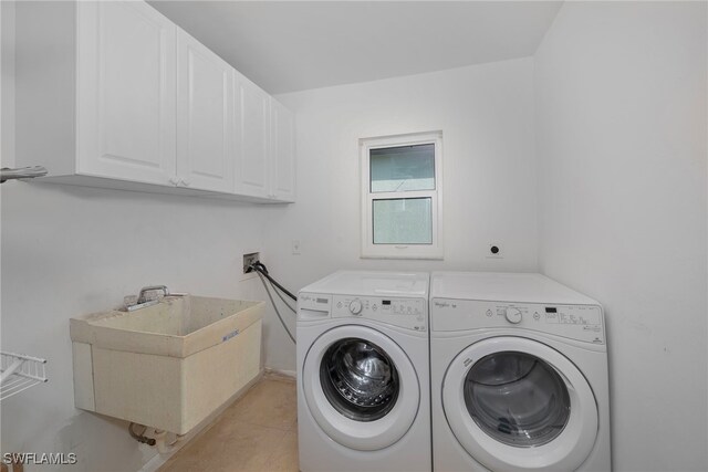 washroom featuring cabinets, light tile patterned floors, washing machine and clothes dryer, and sink