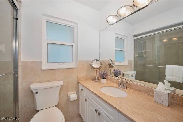 bathroom featuring toilet, vanity, a shower with door, and tile walls