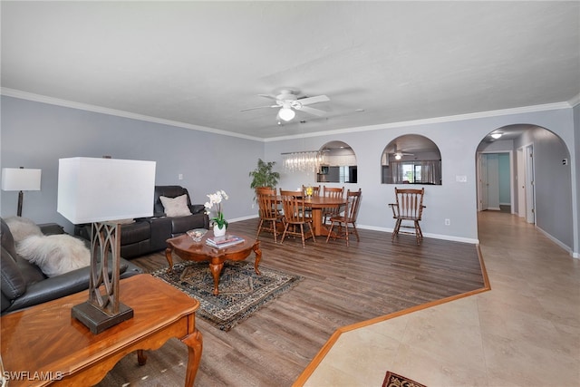 living area with baseboards, arched walkways, ceiling fan, ornamental molding, and wood finished floors