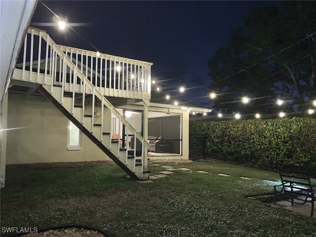 property exterior at twilight featuring a sunroom, stairs, and a lawn