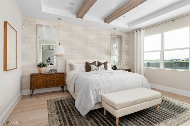 bedroom with baseboards, beamed ceiling, and light wood finished floors