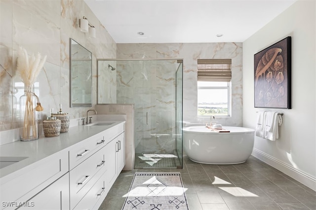 full bathroom featuring a freestanding tub, a sink, tile walls, a marble finish shower, and double vanity