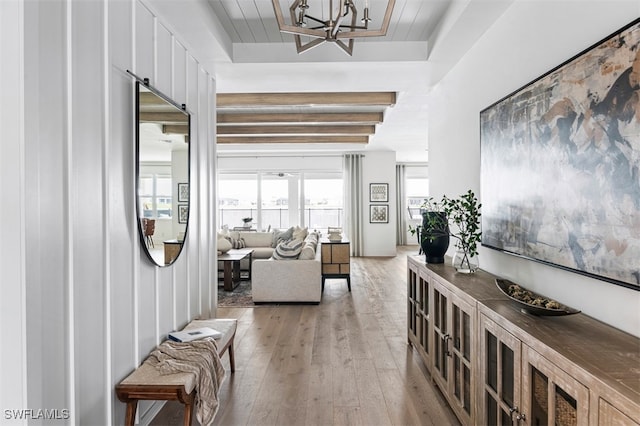 entrance foyer with a chandelier, a tray ceiling, and light wood-style floors