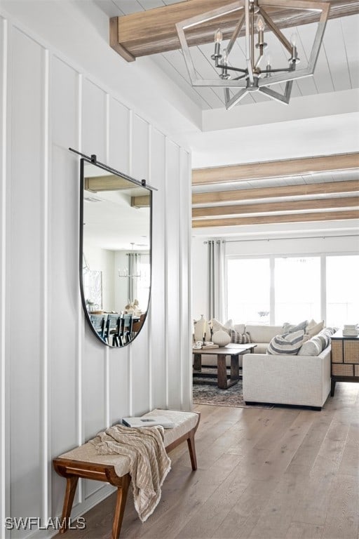 hallway featuring light wood-type flooring, beam ceiling, a decorative wall, and a wealth of natural light