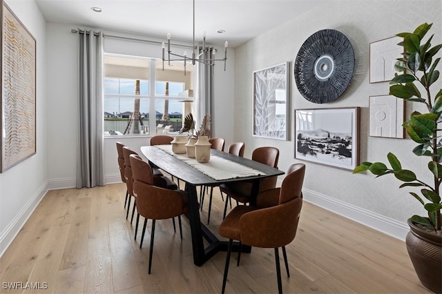 dining area featuring light wood finished floors, baseboards, and a notable chandelier