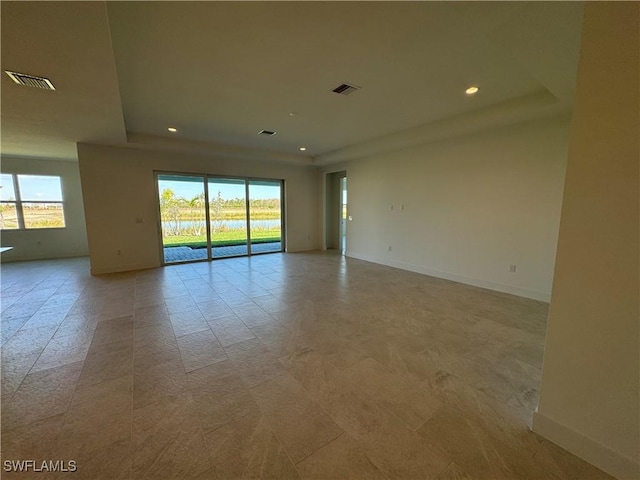 spare room with a healthy amount of sunlight, visible vents, and baseboards