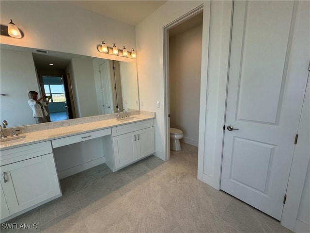 full bath featuring double vanity, baseboards, toilet, and a sink