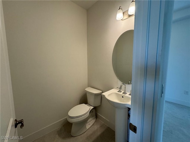 bathroom featuring tile patterned flooring, baseboards, a sink, and toilet