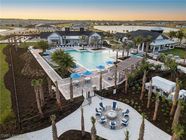 community pool featuring a fire pit, a patio area, fence, and a residential view