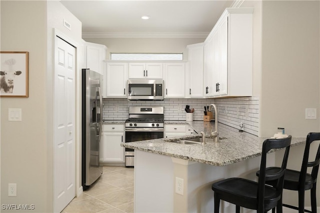 kitchen with sink, light tile patterned floors, appliances with stainless steel finishes, white cabinets, and light stone counters