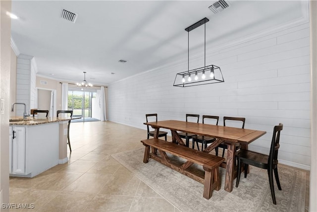 dining area featuring brick wall, sink, a chandelier, light tile patterned floors, and crown molding