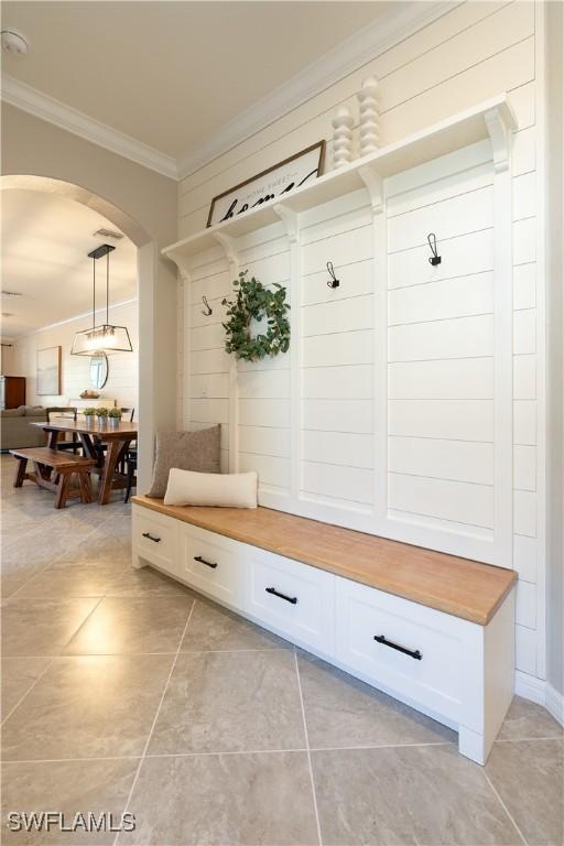 mudroom with crown molding and light tile patterned flooring