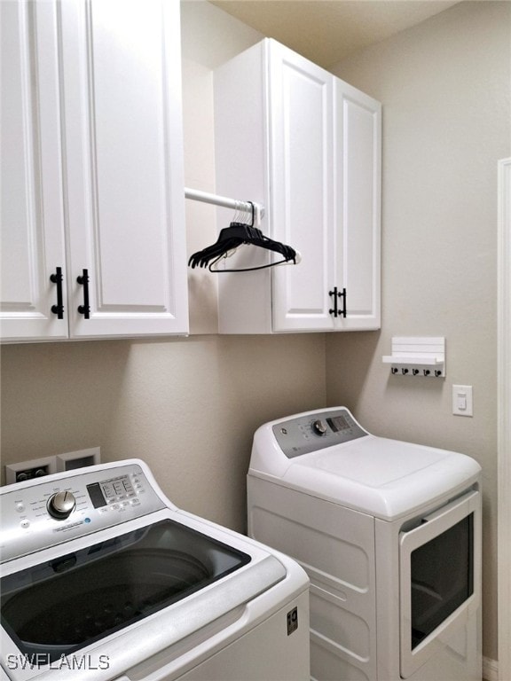 washroom featuring cabinets and washer and clothes dryer