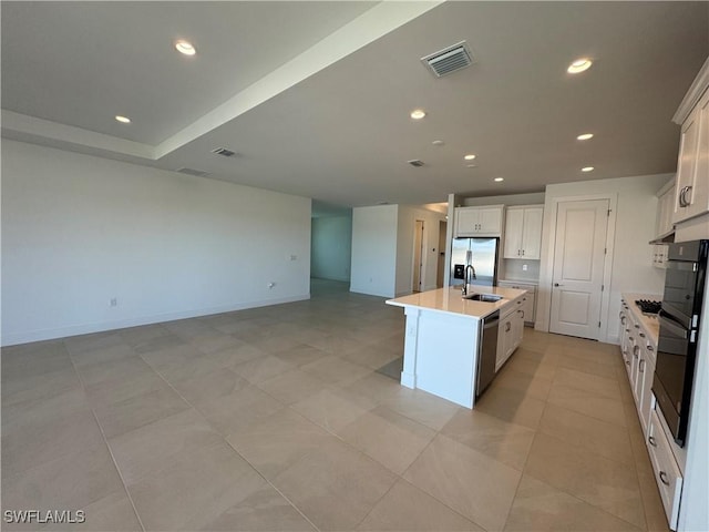 kitchen with white cabinets, stainless steel appliances, a kitchen island with sink, and sink