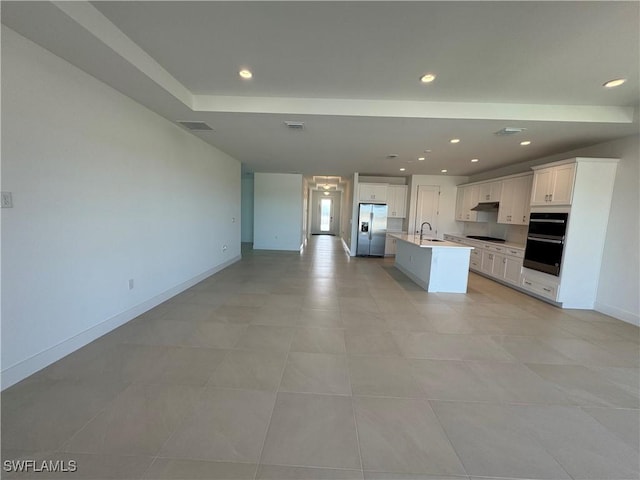 kitchen featuring a center island with sink, open floor plan, under cabinet range hood, black appliances, and a sink