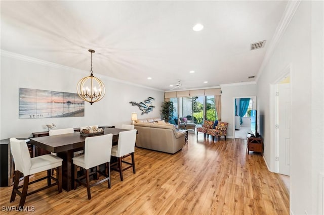 dining room with ceiling fan with notable chandelier, light wood-type flooring, and crown molding