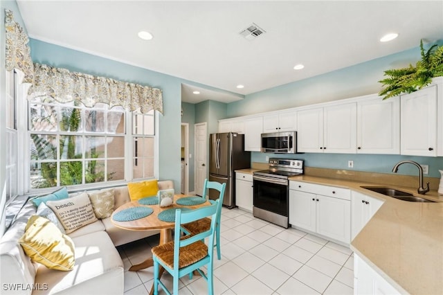 kitchen featuring light tile patterned flooring, stainless steel appliances, white cabinetry, and sink