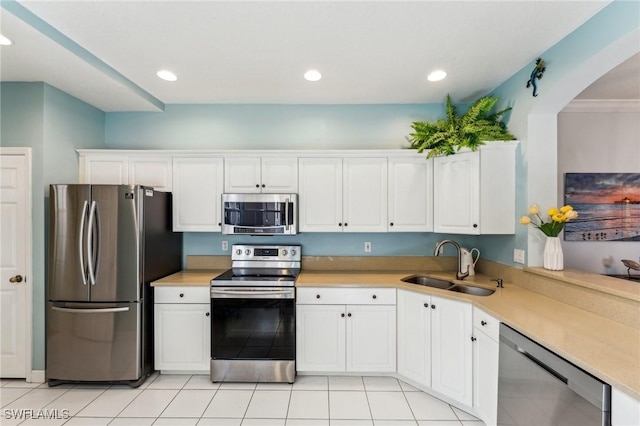 kitchen featuring sink, light tile patterned floors, ornamental molding, white cabinetry, and stainless steel appliances