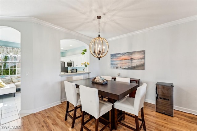 dining room featuring a chandelier, light hardwood / wood-style floors, and crown molding