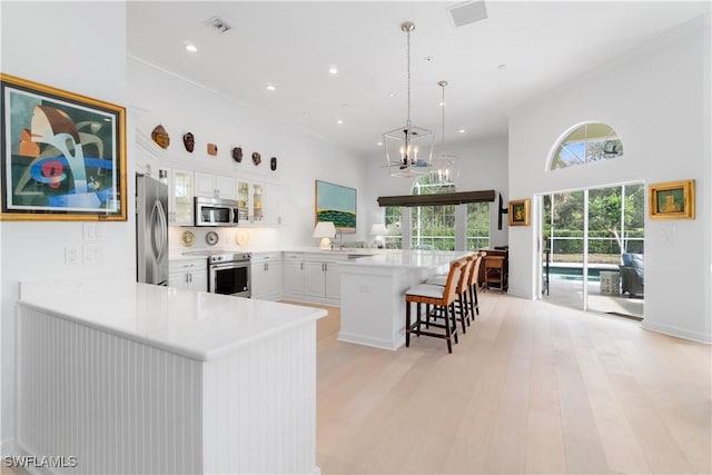 kitchen featuring stainless steel appliances, white cabinetry, kitchen peninsula, and a kitchen breakfast bar