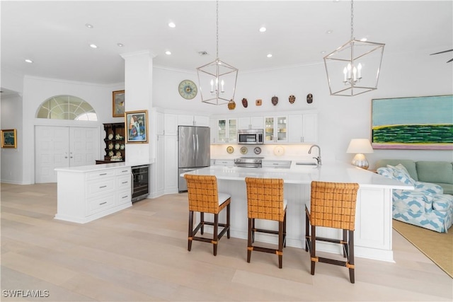 kitchen with decorative light fixtures, white cabinets, a kitchen bar, beverage cooler, and stainless steel appliances