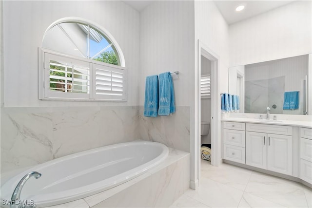 bathroom featuring vanity, toilet, and tiled tub