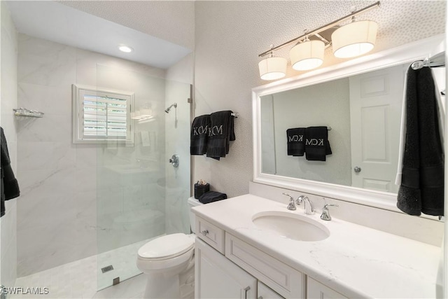 bathroom with toilet, vanity, and a tile shower