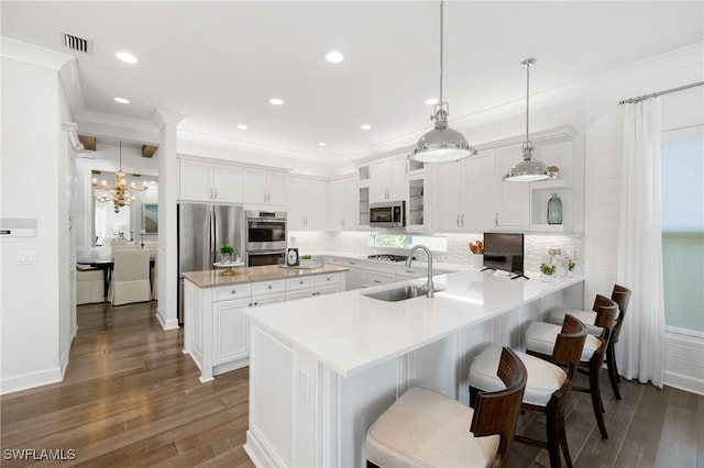 kitchen with appliances with stainless steel finishes, dark hardwood / wood-style flooring, white cabinetry, and pendant lighting