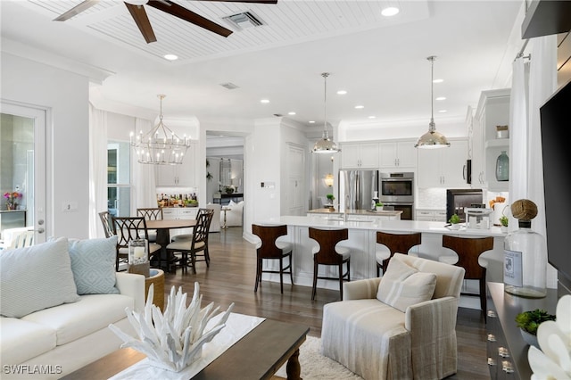 living room with ceiling fan with notable chandelier, dark hardwood / wood-style floors, and crown molding