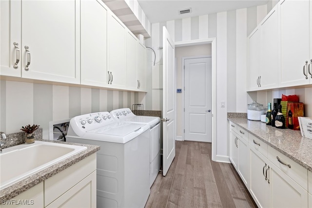 washroom featuring separate washer and dryer, sink, cabinets, and light hardwood / wood-style floors