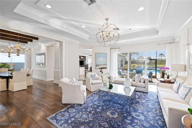 living room featuring a chandelier, a raised ceiling, dark wood-type flooring, and crown molding