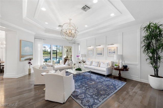 living room featuring a chandelier, dark hardwood / wood-style flooring, and a tray ceiling