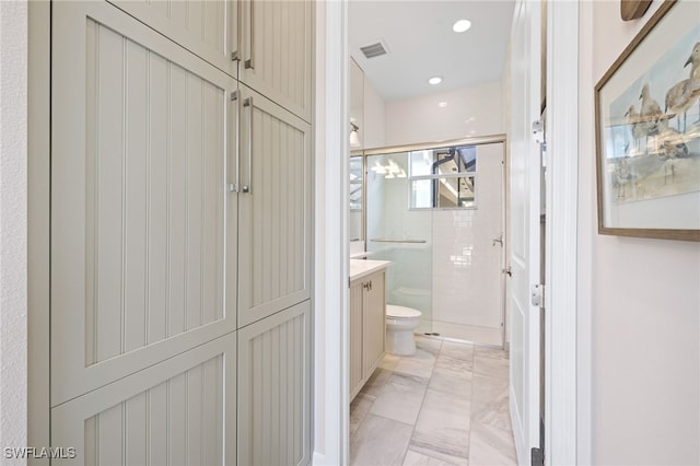 bathroom featuring vanity, toilet, and a shower with shower door