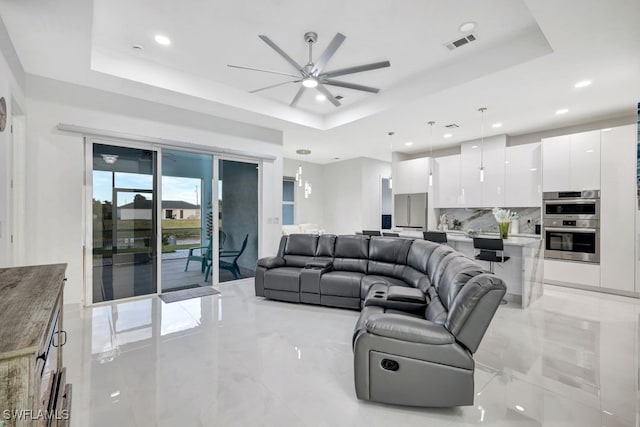 living room featuring ceiling fan and a tray ceiling