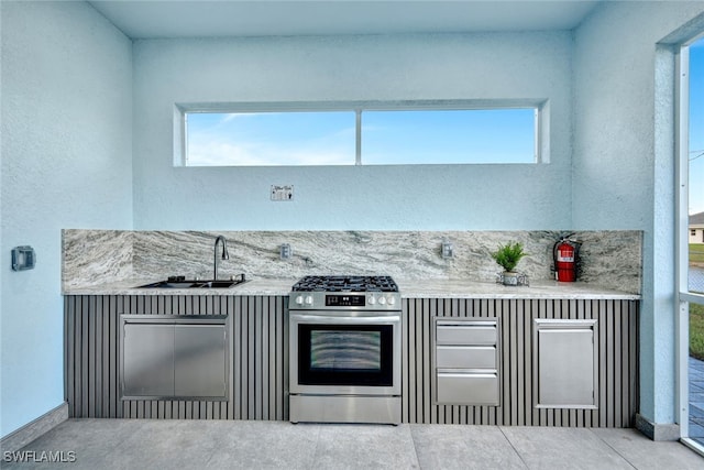 kitchen featuring sink, backsplash, and stainless steel range with gas stovetop