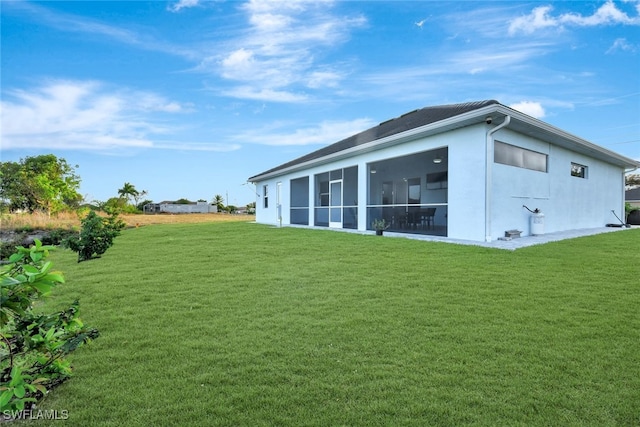 rear view of property featuring a sunroom and a yard