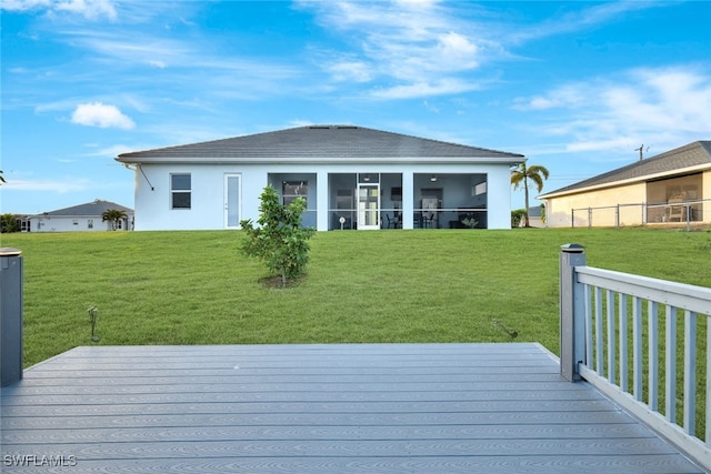 rear view of property with a sunroom, a yard, and a wooden deck