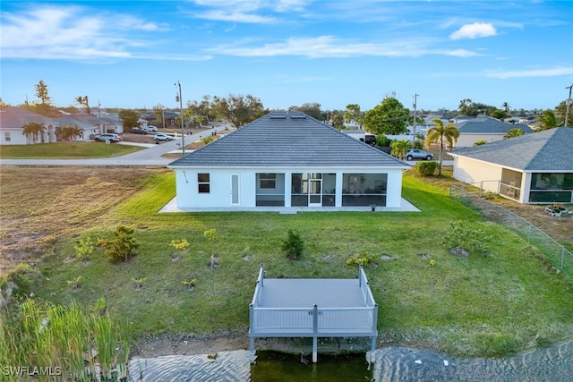 rear view of house featuring a yard, a wooden deck, and a sunroom