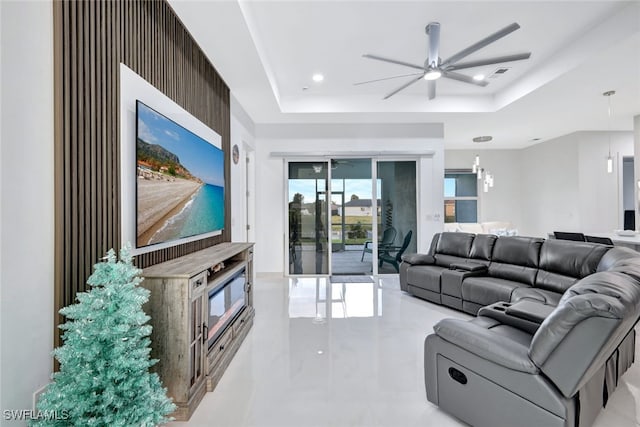 living room with ceiling fan and a raised ceiling