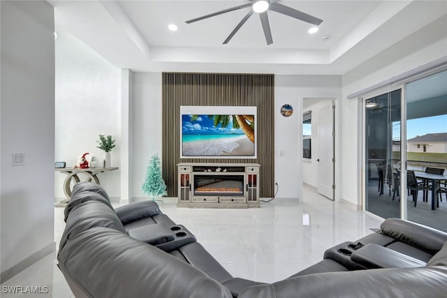 home theater featuring ceiling fan, a fireplace, and a tray ceiling