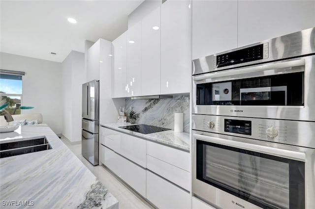 kitchen with light stone countertops, decorative backsplash, white cabinetry, and stainless steel appliances