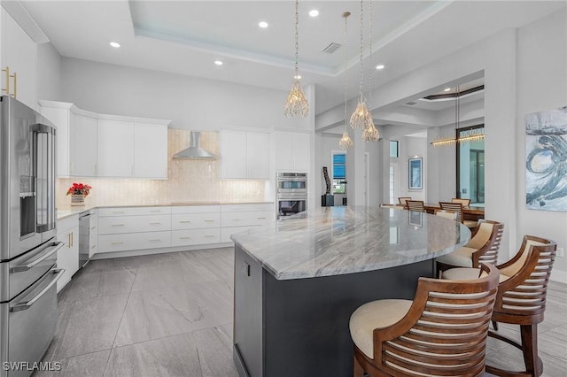 kitchen featuring a large island, a raised ceiling, white cabinetry, and appliances with stainless steel finishes