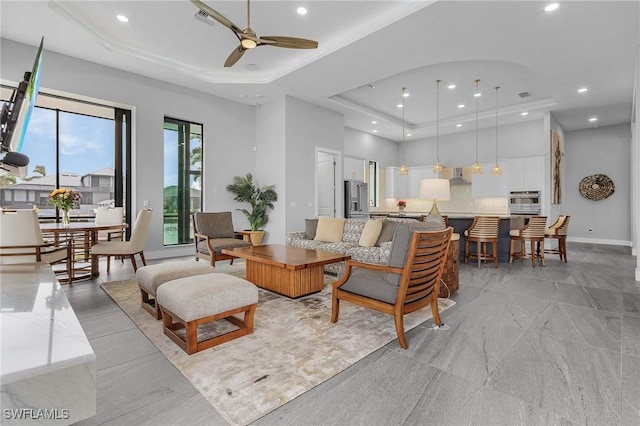 living room with ceiling fan and a raised ceiling