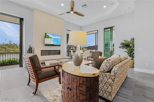 tiled living room featuring ceiling fan, a fireplace, and a wealth of natural light