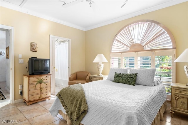 bedroom with ceiling fan, light tile patterned floors, ornamental molding, and ensuite bath