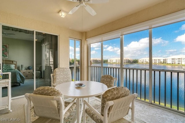 sunroom with ceiling fan and a water view